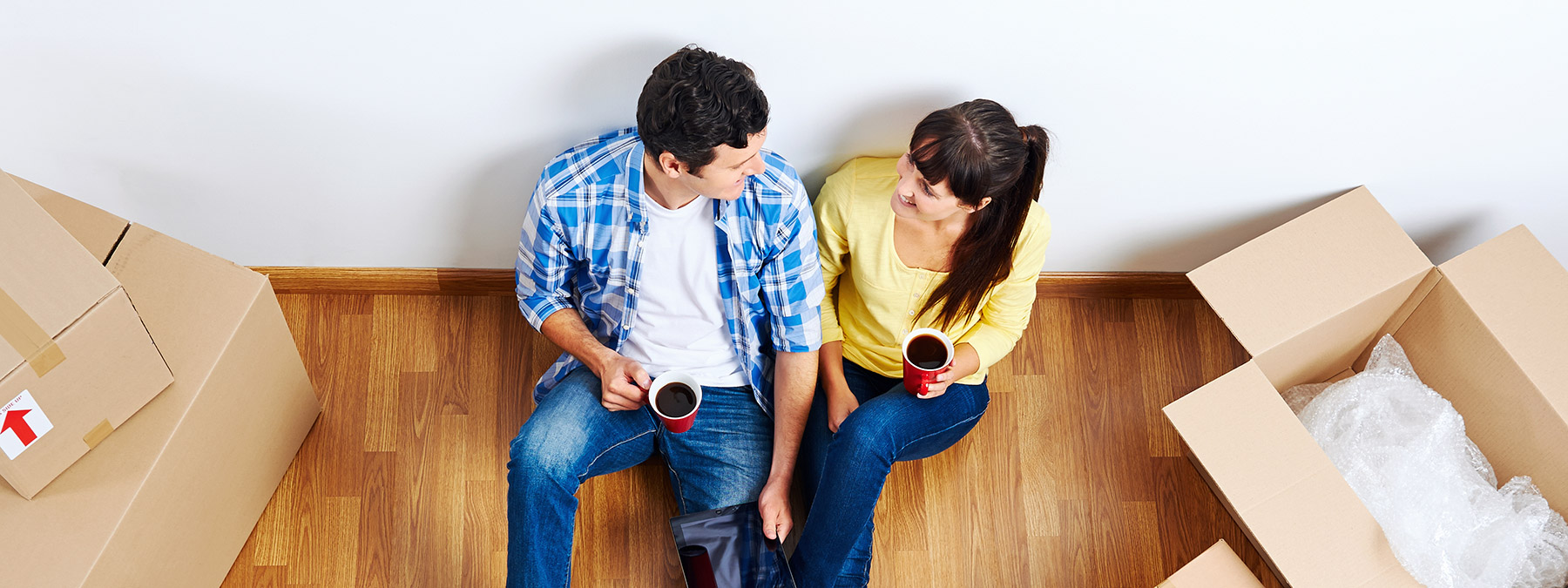A young couple shares a cup of coffee on the floor of their new home